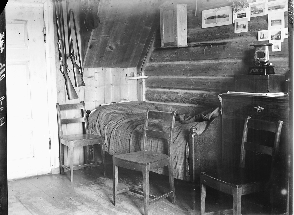 Ringsaker, Moelv, Simen Baardseths soverom i "fargeriet" bodde 2. etasje i Lindal, det første hus nærmest brua sør  i Moelv, gevær og fotografier på veggen,