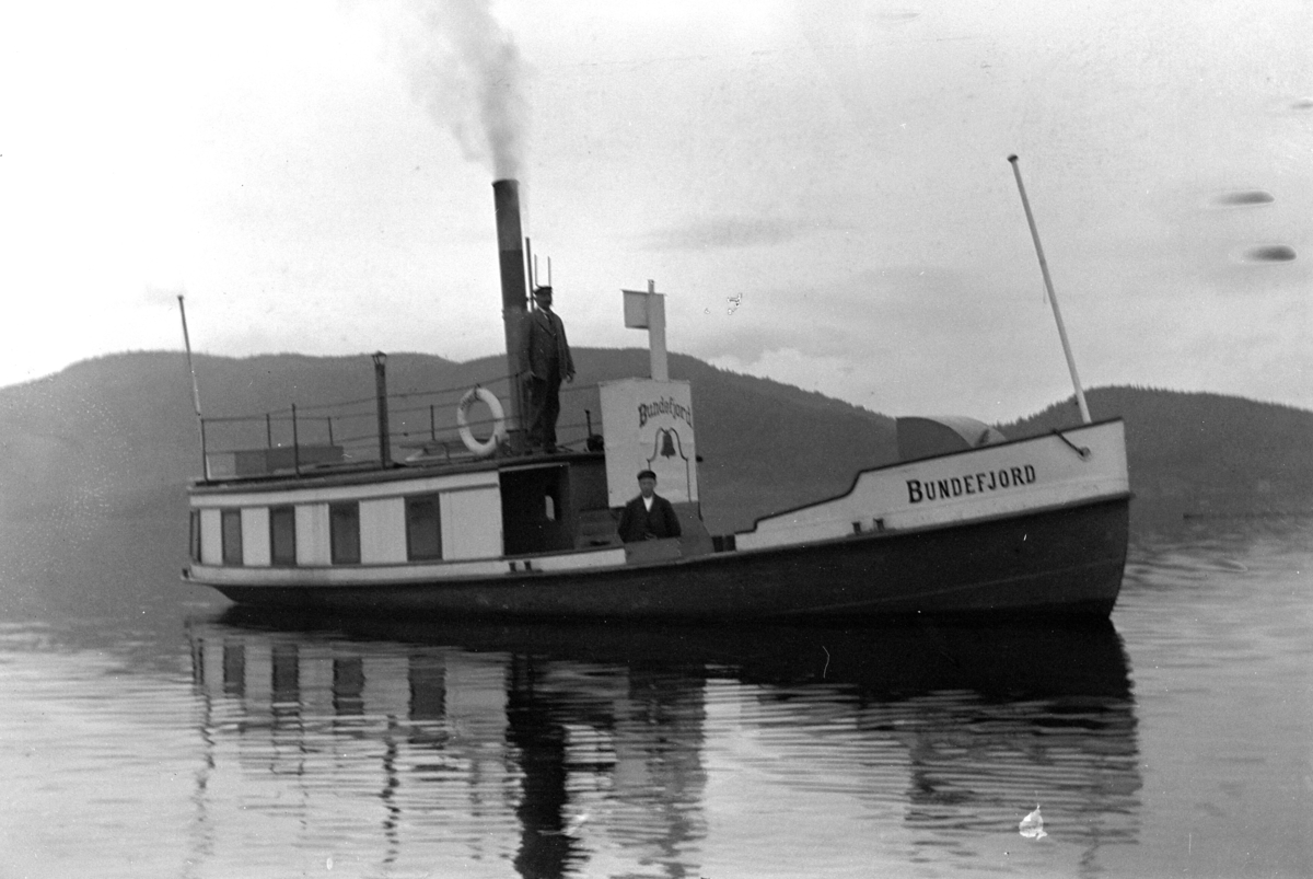 Brumunddal, D/S Bundefjord, dampbåt, Mjøsbåt utenfor Nerkvern gård og brenneri, Kaptein Ganes på brua, før ombyggingen i 1909. Anskaffet 1876 og gikk først under navnet D/S Prøven og holdt til på Lillehammer.