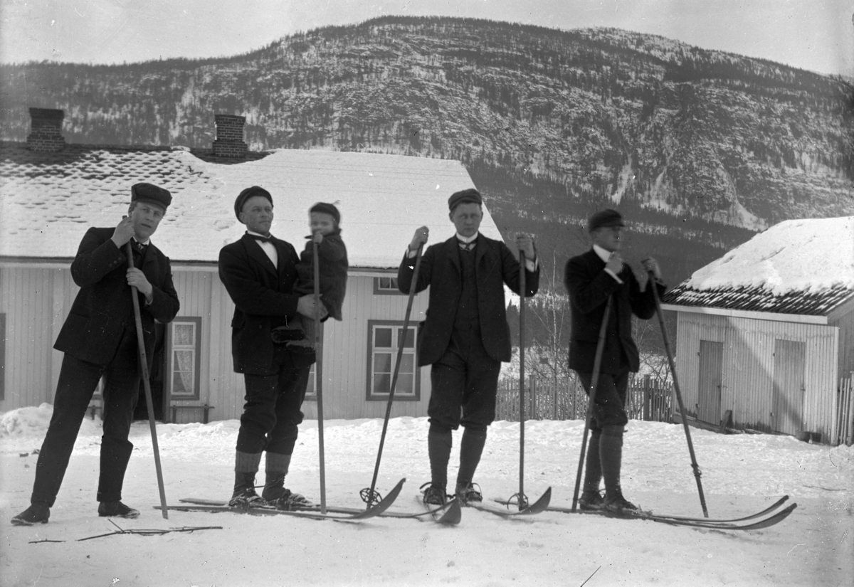 Fire menn, den ene med en gutt i armene, på ski i Hunder, Gudbrandsdalen. 