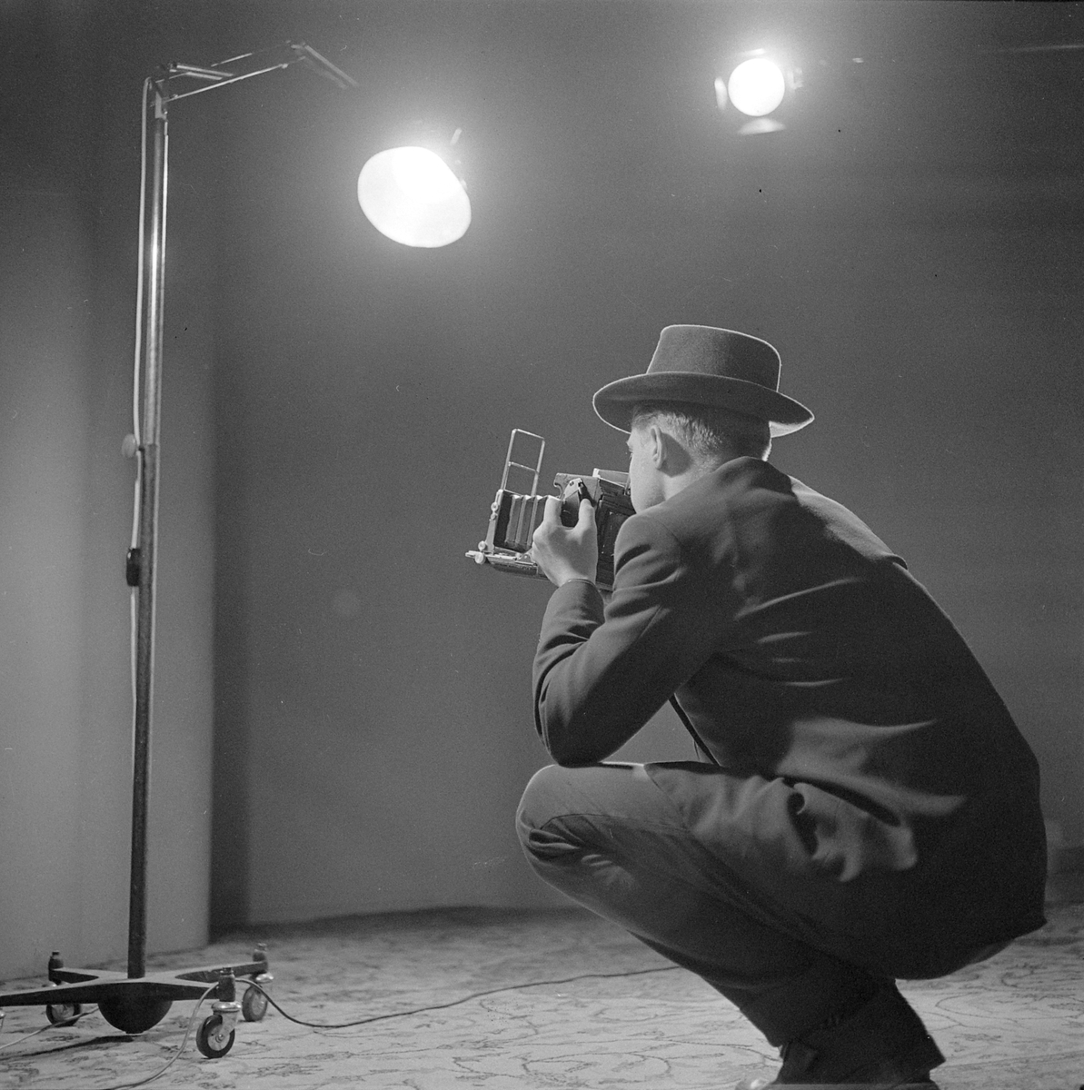 Fotograf med Speed Graphic pressekamera i fotostudio