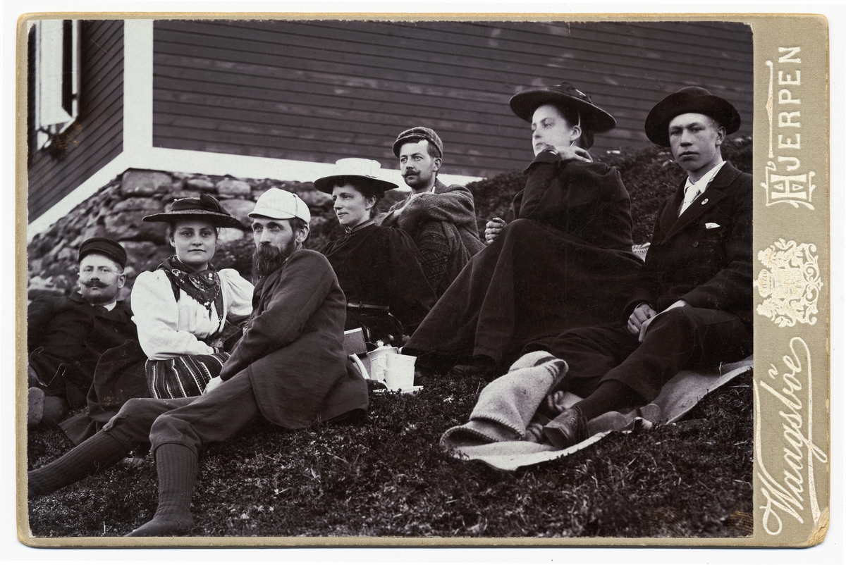 Gruppbild utanför Sylstugan vid invigningen 1897. Män och kvinnor sittande i slänt utanför raststuga.