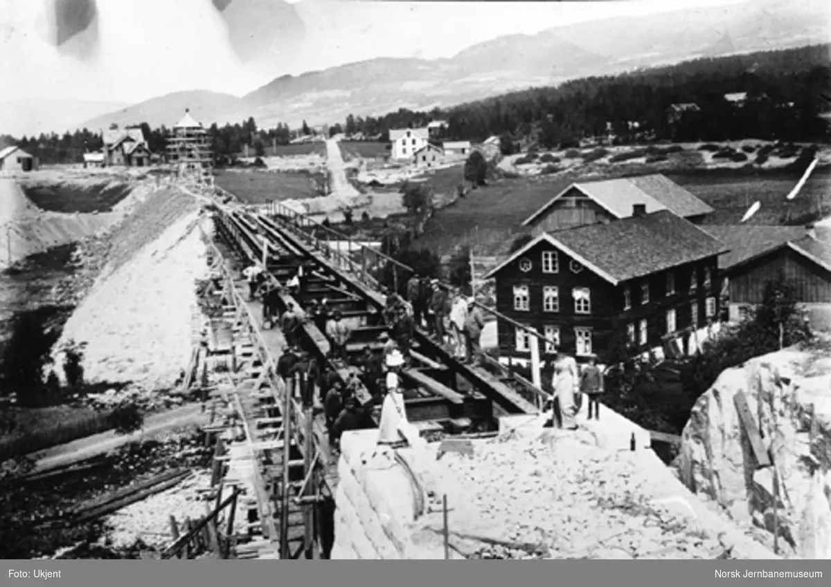 Hamar-Selbanens anlegg; bygging av bru over Moelva, stasjonsområdet med bygninger og vanntårn i bakgrunnen