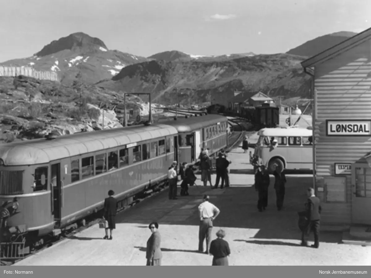 Lønsdal stasjon med reisende til "Nordlandsekspressen" fra ankommende buss; motorvogn type 6 nr. 18262 fremst.