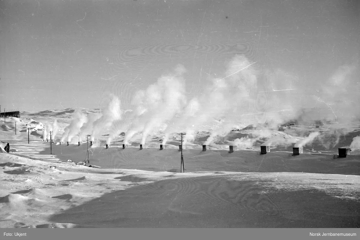 Røyk fra passerende tog siver ut av snøoverbygg