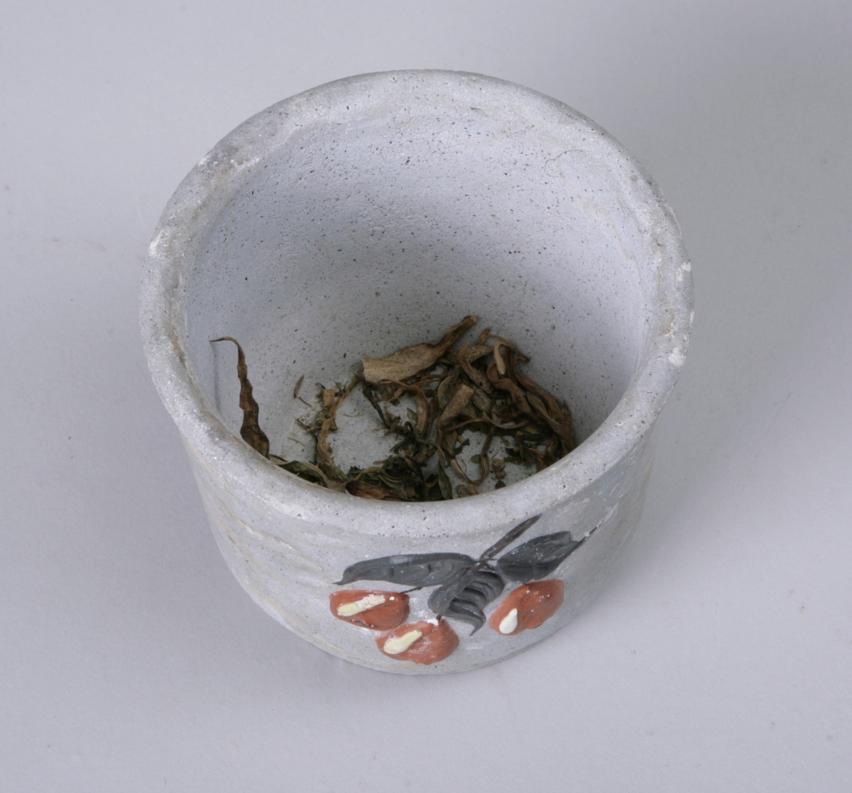 Sylinderformet potte til å sette blomsterpotter i. Dekorert med påmalte blader og bær.