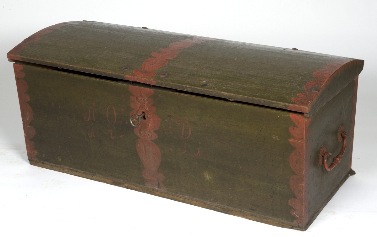 Kiste med buet lokk, grønnmalt med røde båns. Innvendig umalt og med leddik. Beslag på innsiden av lokket har hjerteformede hull med vevd rødt ullstoff i.