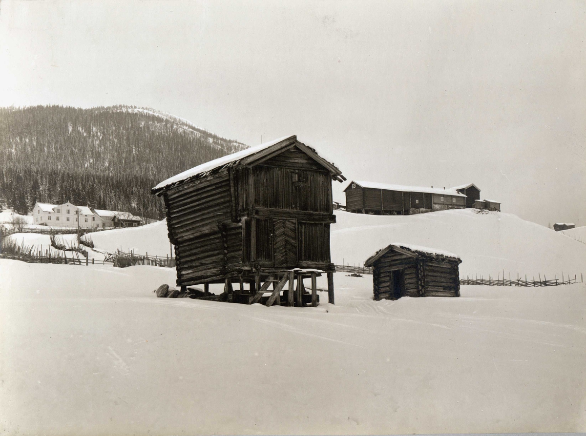 Den gamle prestegård. Øvre Rendal, Nord-Østerdal. Stabbur i snølandskap, låve og våningshus i bakgrunnen.