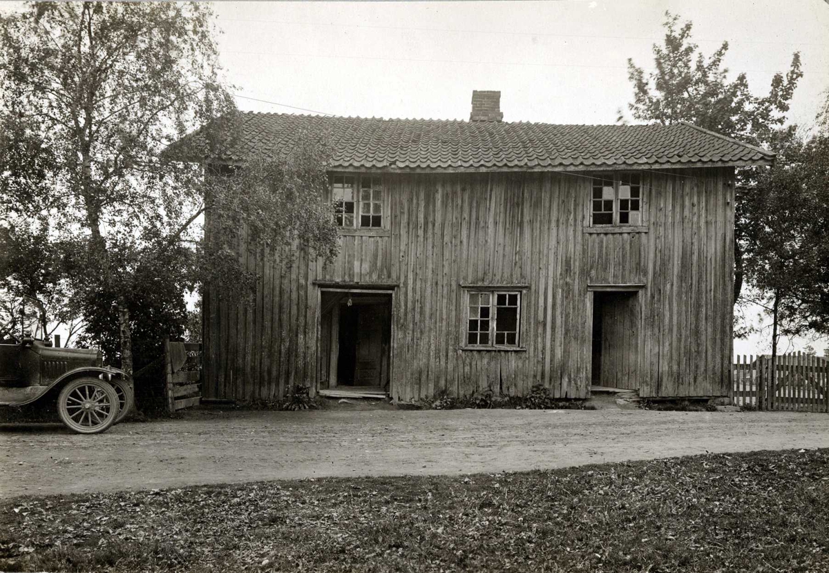 Lodding, Ullensaker, Øvre Romerike, Akershus. Hus med to dører og knuste ruter ved vei. Fronten på en bil.