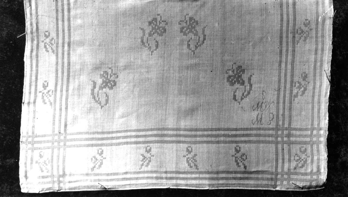 Hvit serviett med strøblomster og bord av striper og blomster. Vevet av Marie Waleur ca. 1850. Norsk hjemmevevet damask.