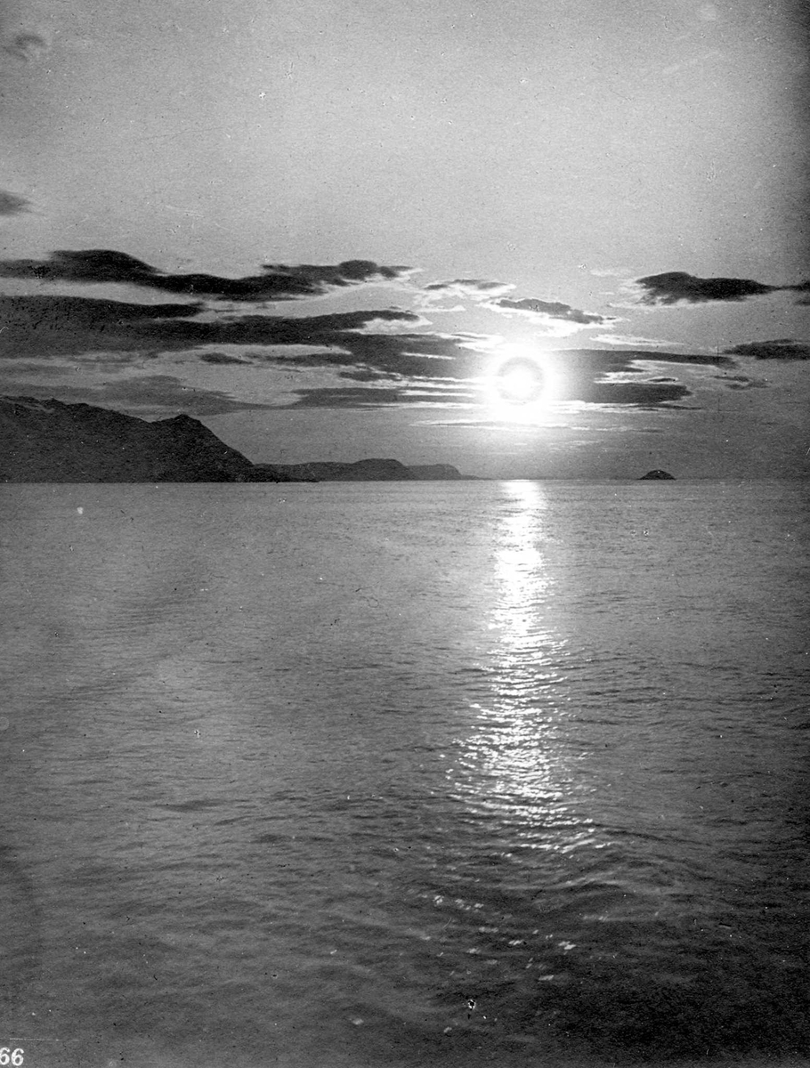 "Midnattsol utenfor Hammerfest." Lav, sterk sol mellom lyskantede skyer, sterk solstripe på vannet. 
