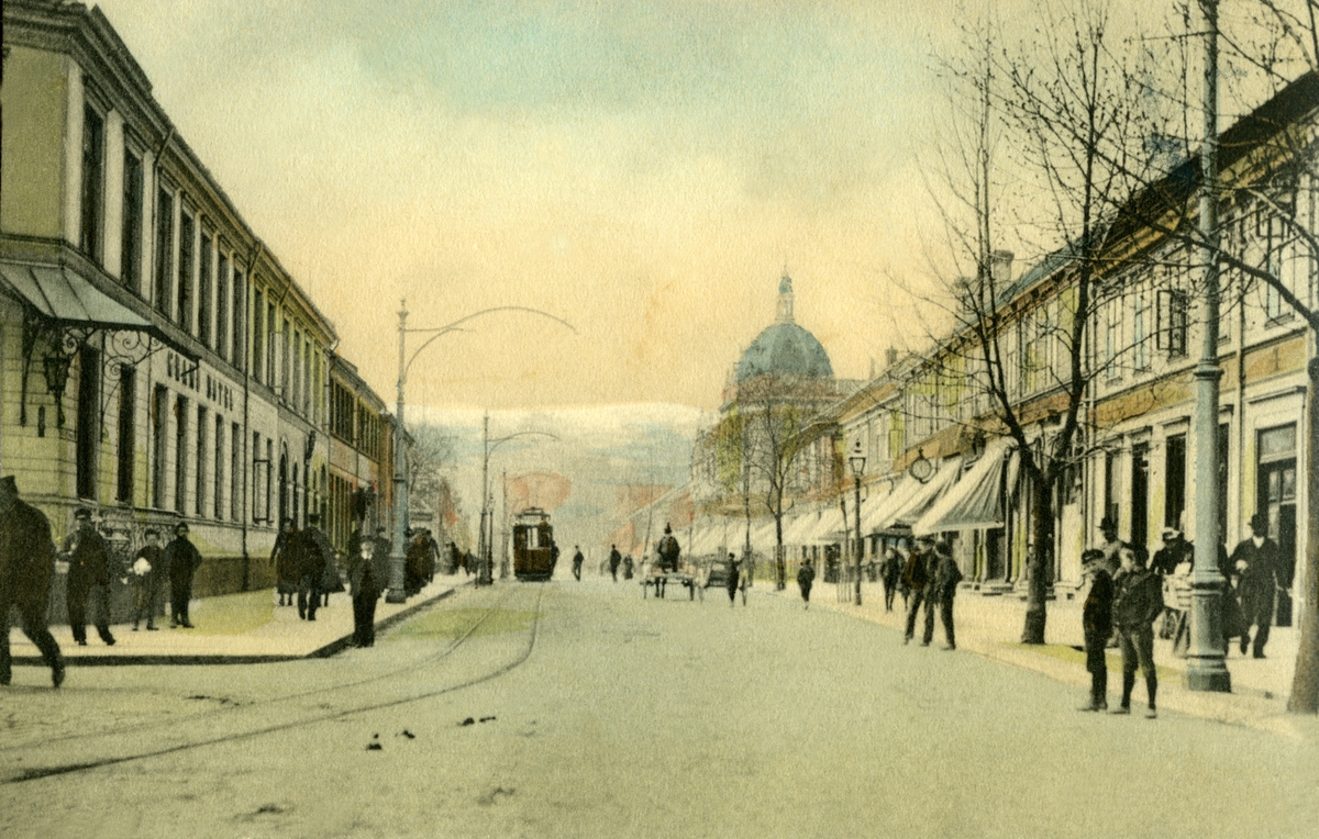 Postkort.  Jule- og nyttårshilsen. Fotografisk motiv. Fra Trondheim: Gate med Grand Hotel. Trikk. Fotgjengere. Datert 22.12.1902.