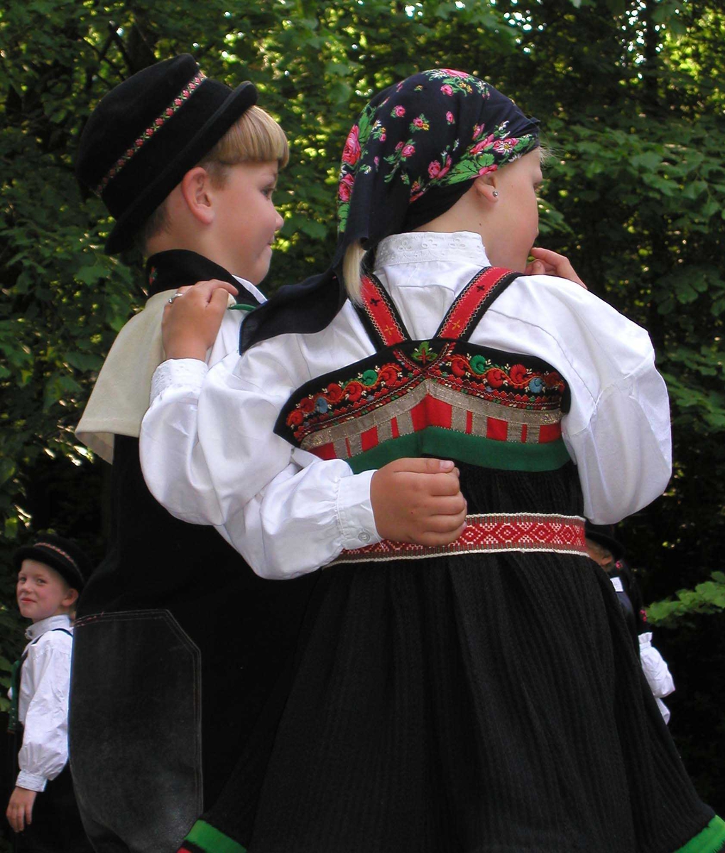 Norsk Folkemuseums dansegruppe, kledd i folkedrakt, danser folkedans i Friluftsteateret, NF239. Dansende par sett bakfra.