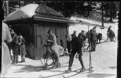 Skiløpere samlet utenfor skihytte i marka. Noen sitter på gj