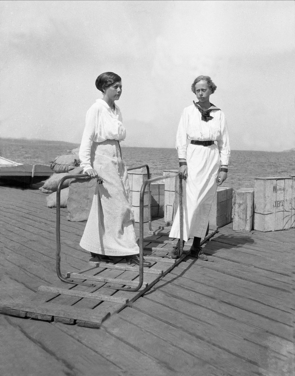 To kvinner står oppstilt på en brygge. Robsahm og Lund.