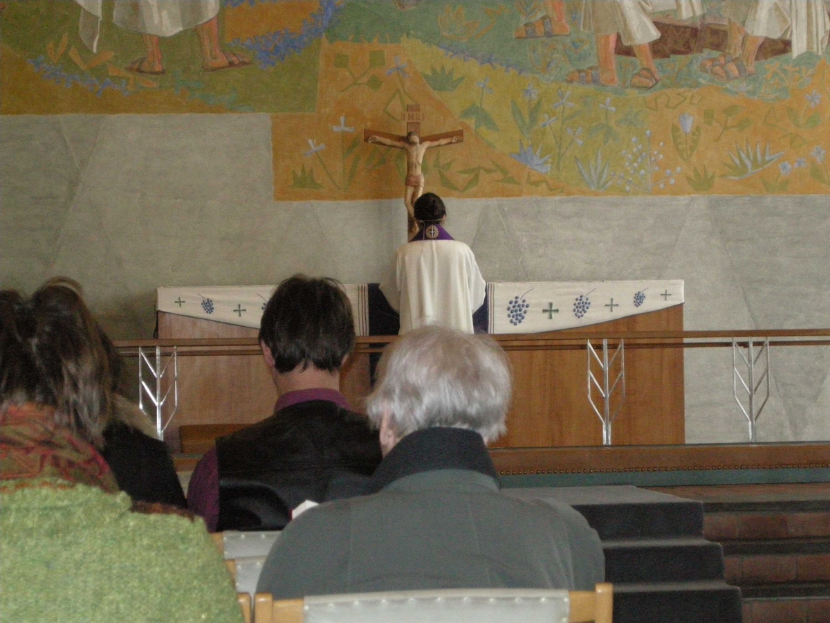 Langfredag i Tonsen kirke, 21.03.2008. Presten, kledd i hvit alba og lilla stola, står med ryggen til oppe ved alteret som er ganske nakent. Kun dekket med hvit alterduk og et lilla klede. Krusifiks.