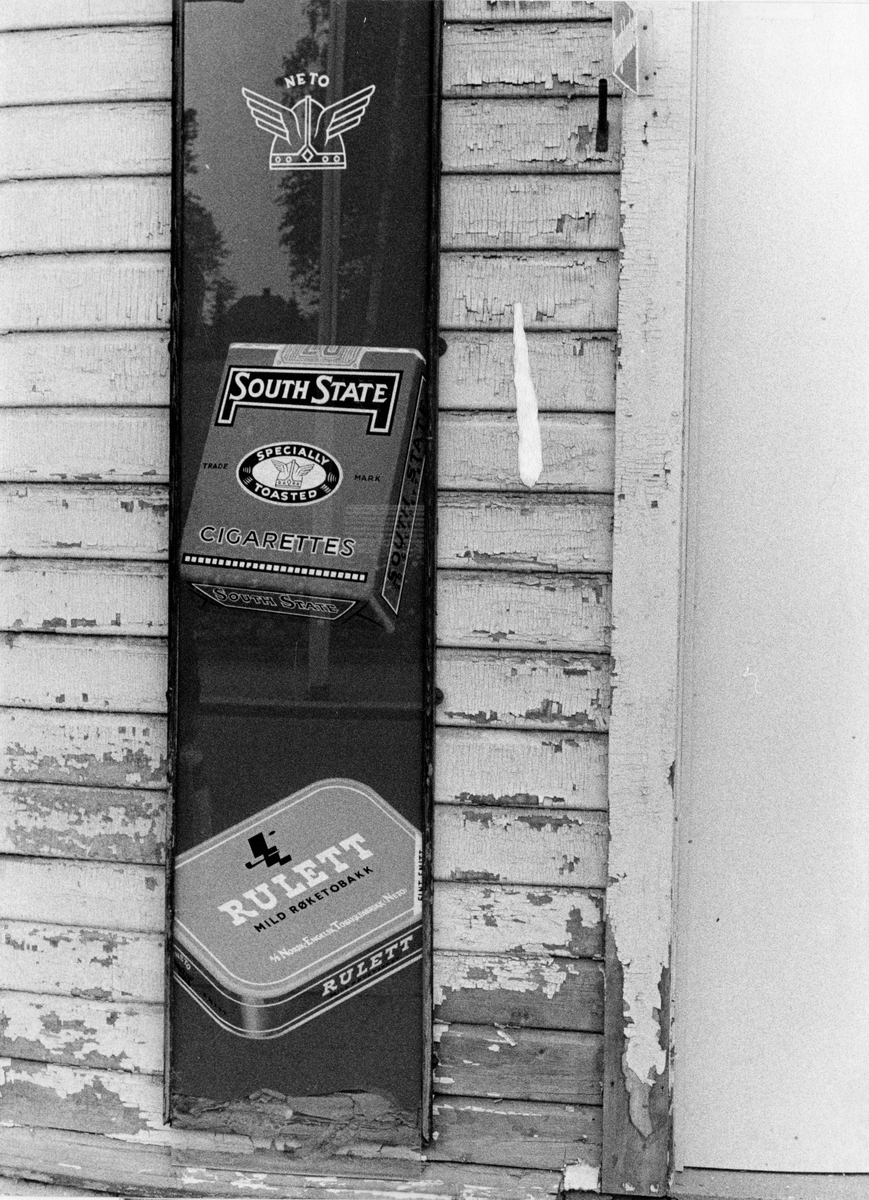 Reklameskilt for South State sigaretter og Rulett tobakk på husvegg.