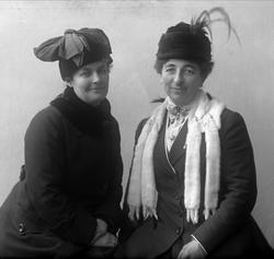 Gruppeportrett, to kvinner i ytterklær med hatter. Fru agent