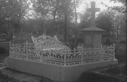 Gravsted, steinstøtte på opphøyd platting med smijernsgjerde