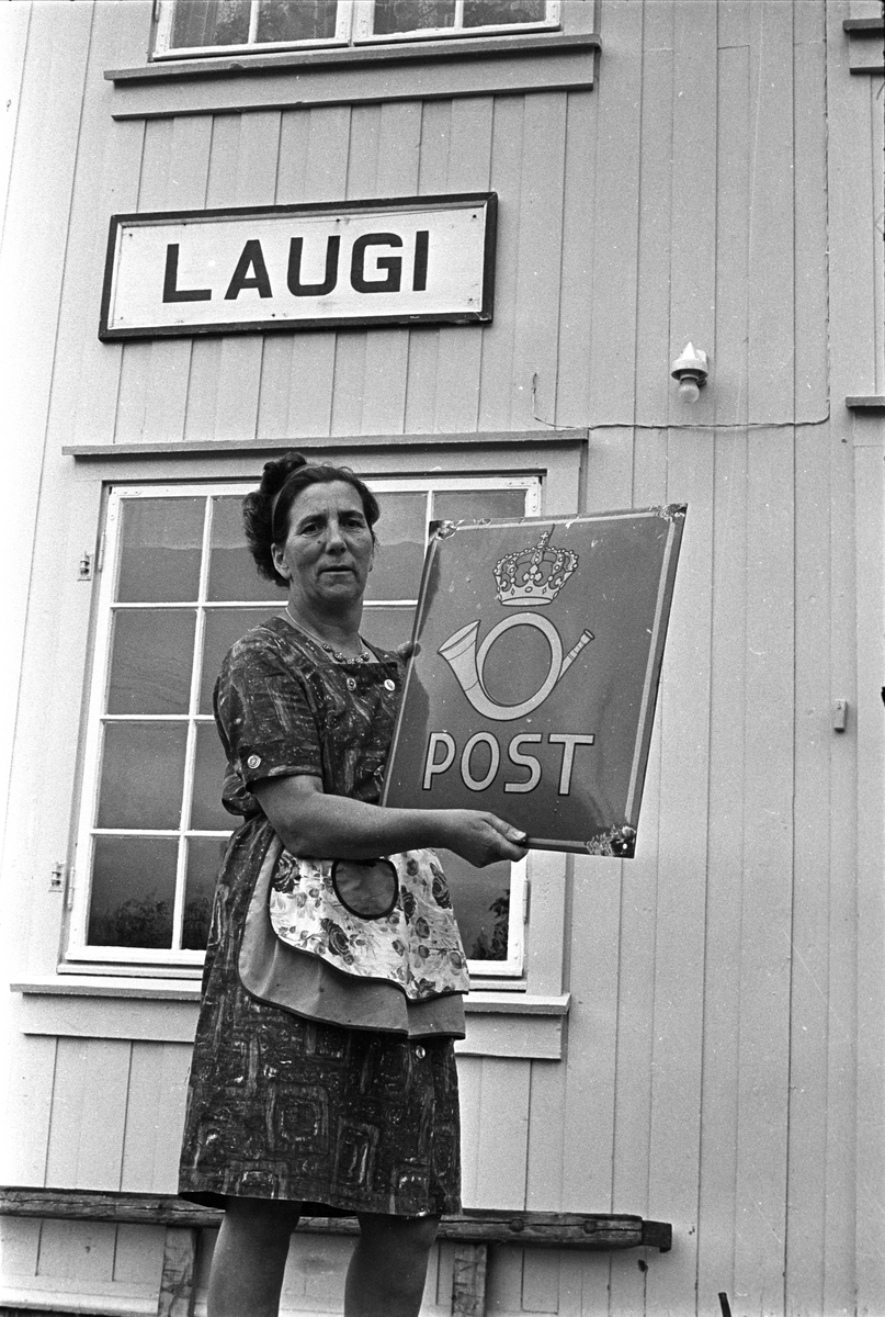 Fra Rollag 1968. Postskilt tas ned av en kvinne på Laugi stasjon.