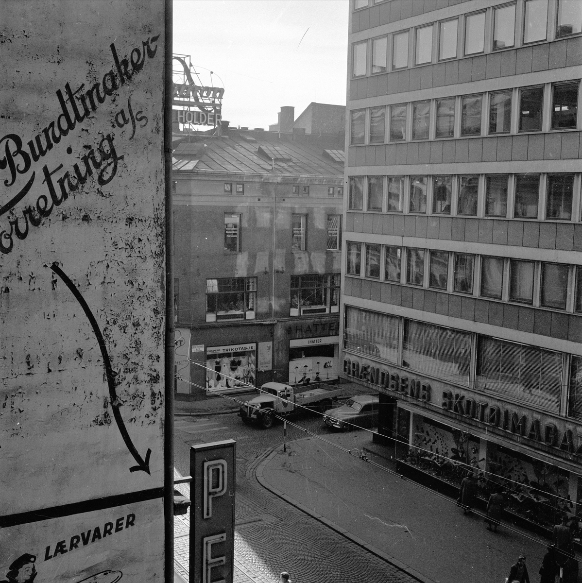 Grændsens Skotøimagasin i Grensen 12 i Oslo. September 1955. Bygate med bygårder og trafikk.