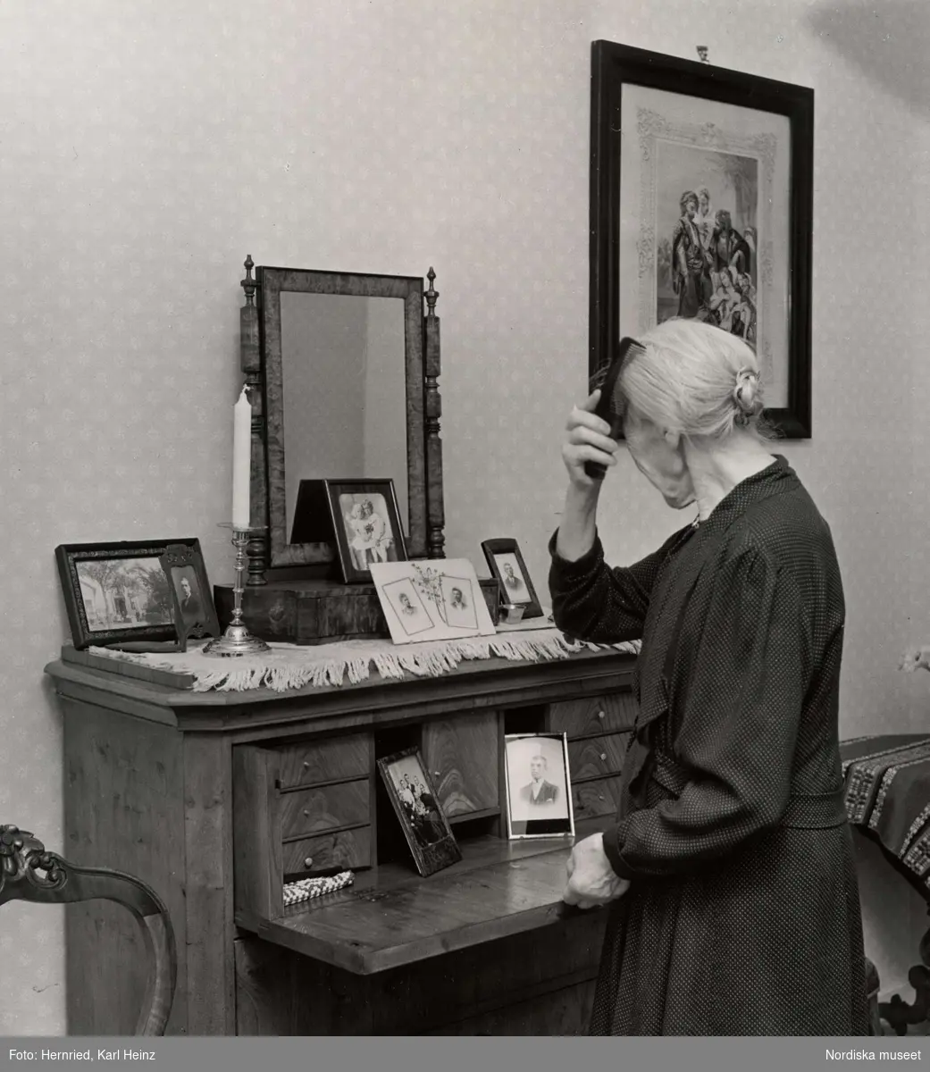 Sundbybergs ålderdomshem, Uppland. Kvinna kammar sitt hår framför spegel i pigtittare