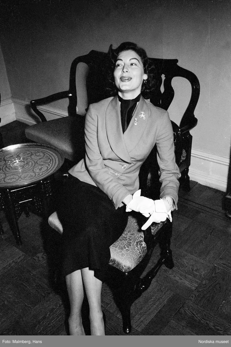  Ava Gardner sitter i en stol. Från reportage om Frank Sinatra på turn i Sverige. Folkets park.