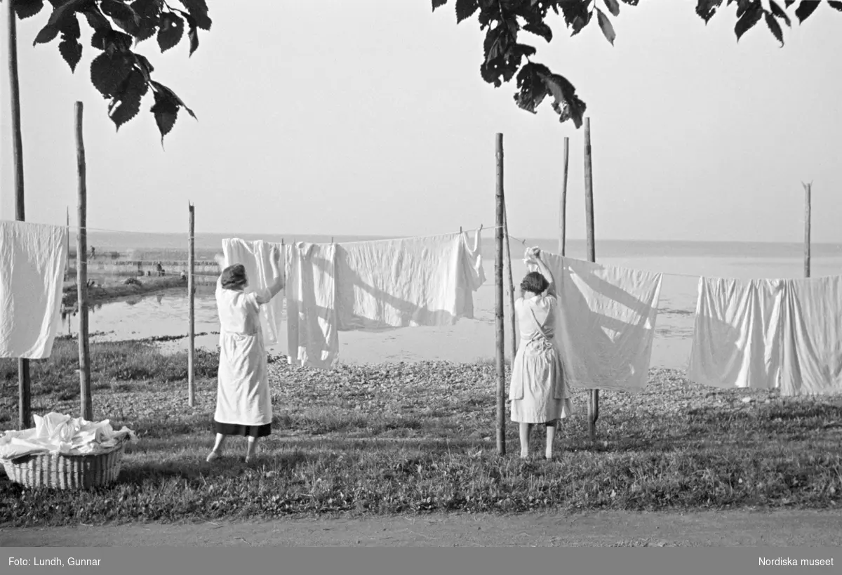 Kvinnor hänger tvätt i Arildsläge, Skåne sommaren 1936. I bakgrunden syns Skälderviken och Bjärehalvön.