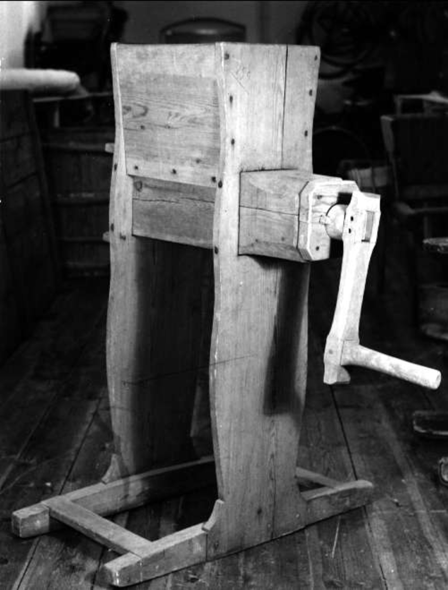 Kvarn, helt av trä med skruv av trä. Mynning 42 x 33 cm, svagt profilerade sidor, bred fot med slåar. Vev med handtag av trä.