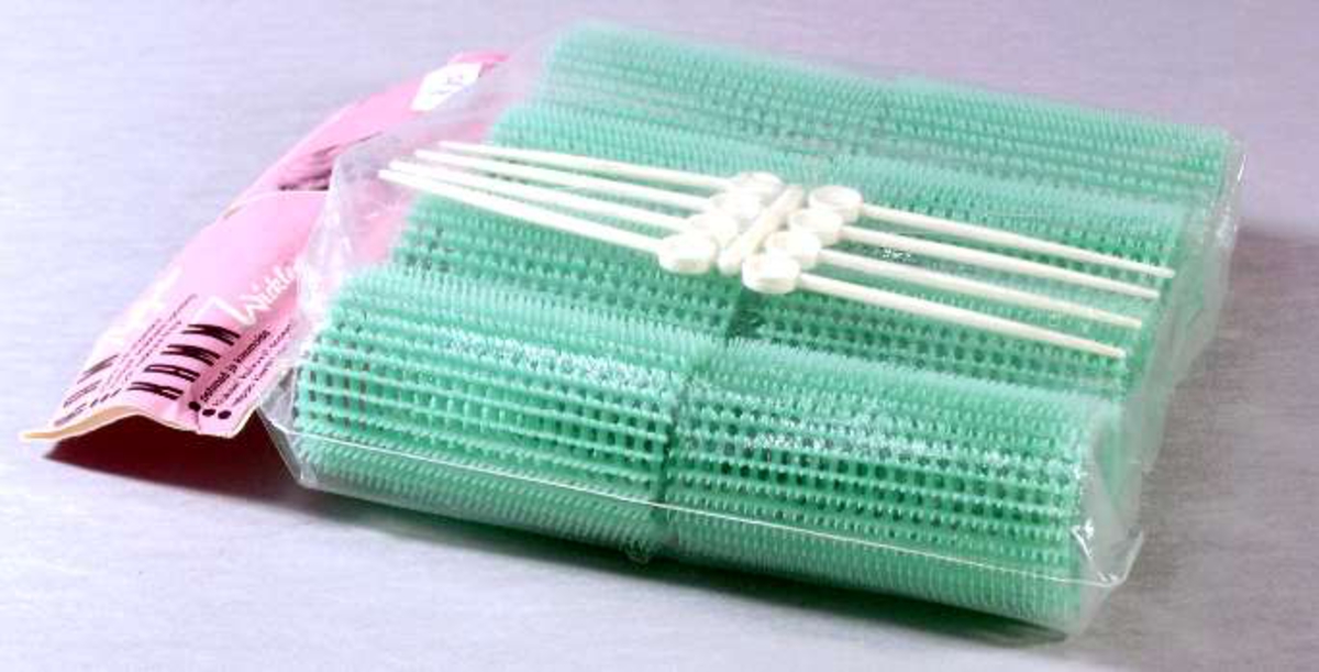 Originalförpackning av plast och papp med åtta gröna papiljotter samt åtta vita papiljottpinnar, allt tillverkat i plast. Förpackningen märkt: "Kam Papiljotter" och "Original STÖHR". Prislapp påklistrad: 2,80.