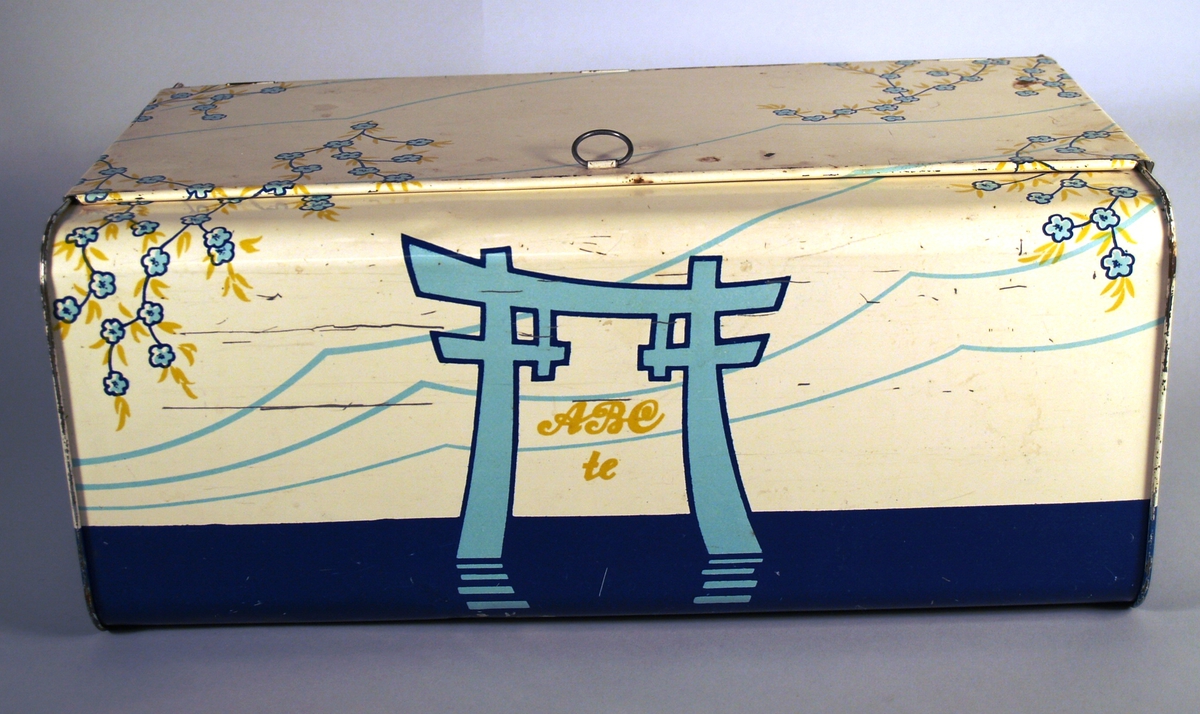 Boksen har ein Kinesisk-prega dekor. Blomstrande kirsebærranker. Båt med seil. Fjell i bakgrunnen.