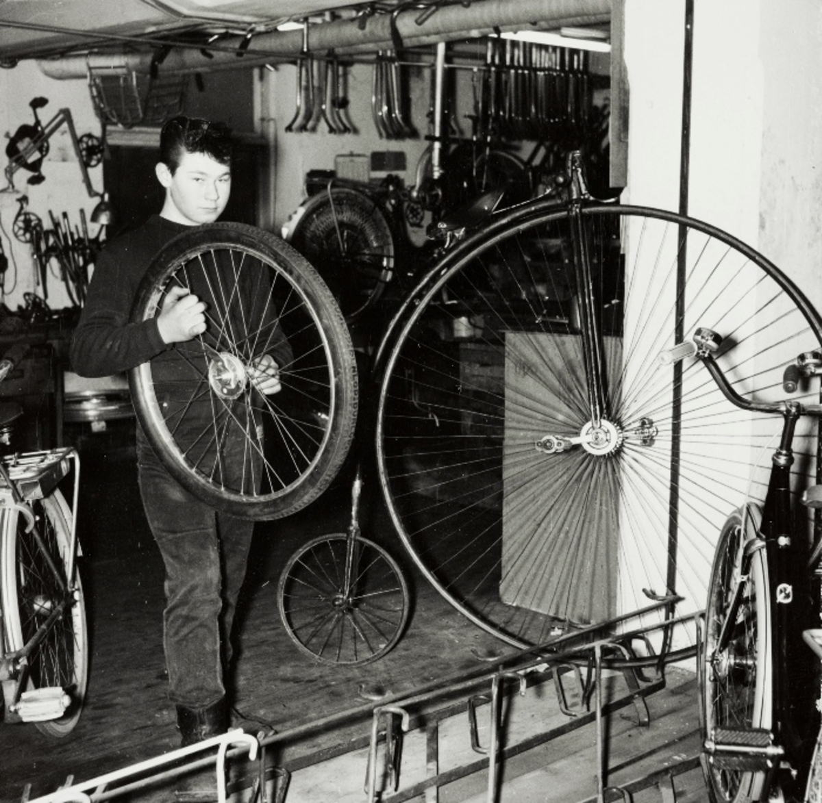 Fredrik Utsola holder på et sykkelhjul i reparasjonsavdelingen ved sykkelfabrikken til Jonas Øglænd, Sandnes, framme står en velociped