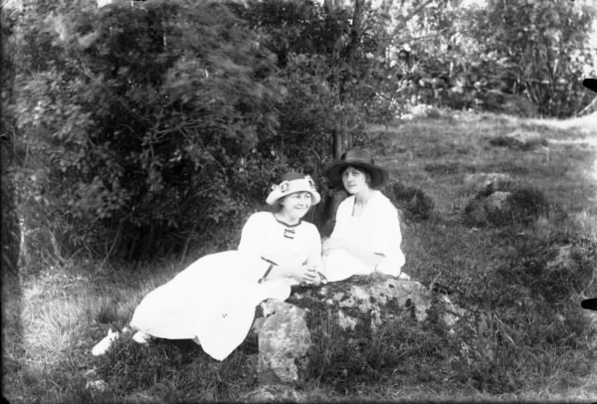 Gruppbild av två kvinnor i vackra hattar i skogen