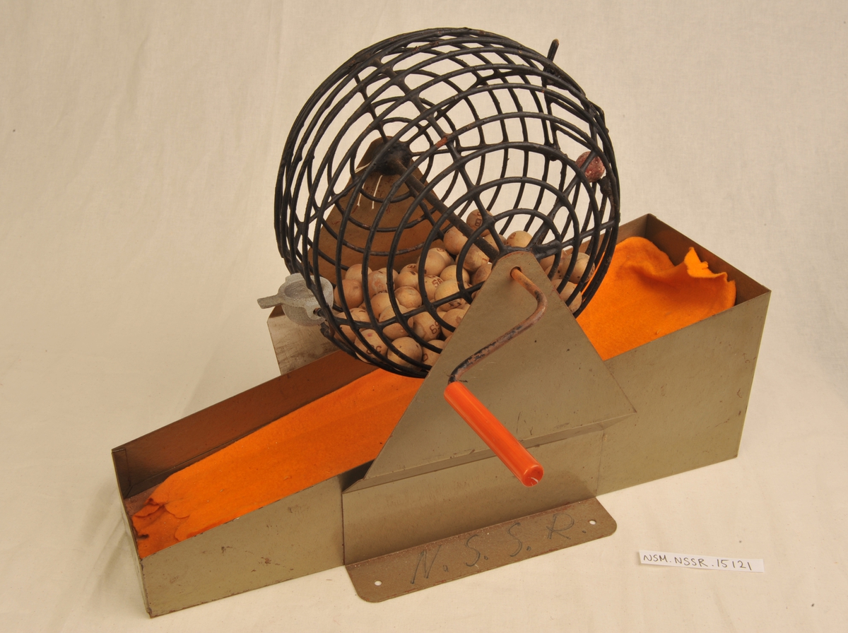 Kule av jern-"netting" inneholdende bingokuler, som blir dreid rundt av håndtak. Kulen hviler på et fundament av stålplater. Under nettingkulen er det en "seng" for oppsamling av bingokulene, kledd med oransje filt.