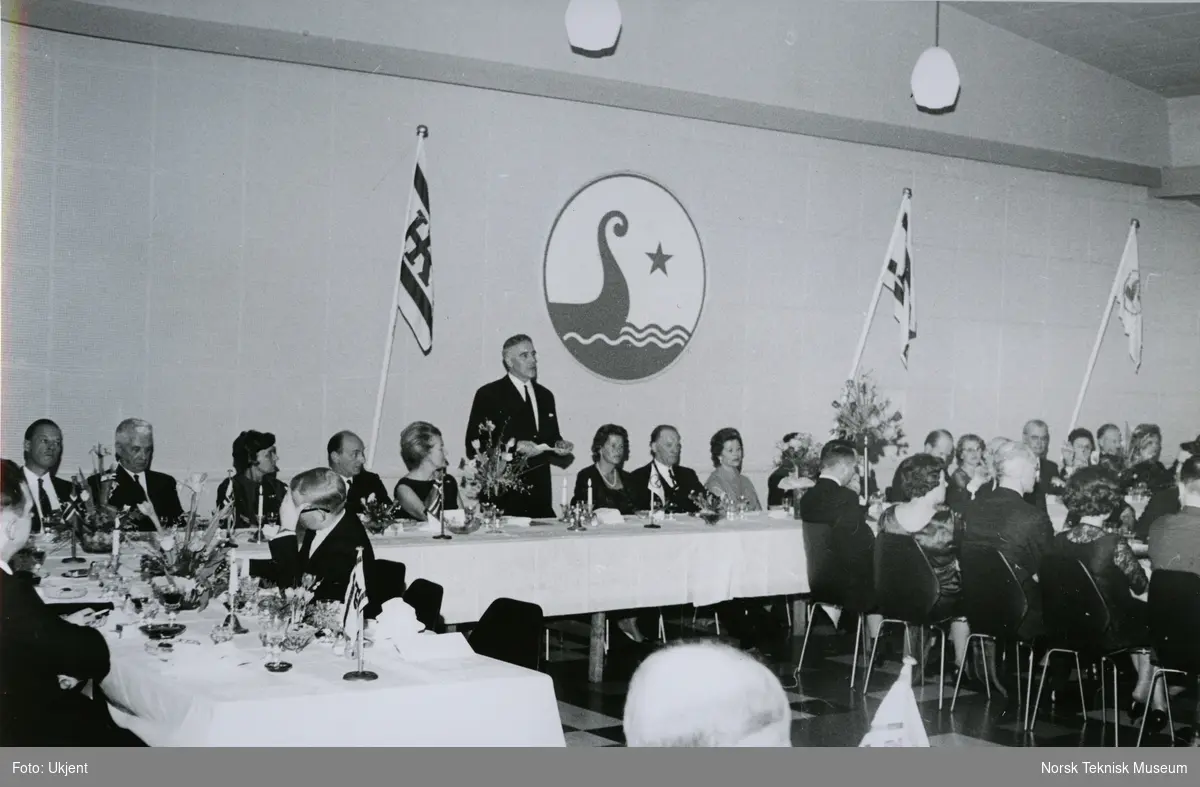 Mann taler under måltid etter dåp av tankeren M/S Julian, B/N 535 (Stords B/N 49) på Stord Verft. Skipet ble levert av Akers Mek. Verksted og Stord Verft i september 1966 til Hilmar Reksten.