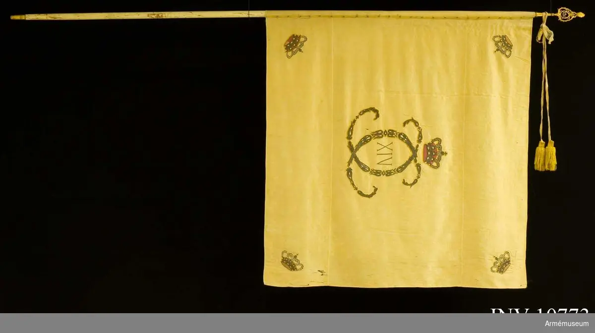 Broderad med silver. Samhörande: Kravatt, vitt siden, 160 cm lång plus tofsar 14 cm. Fanspets med Karl XIV Johans namnchiffer.