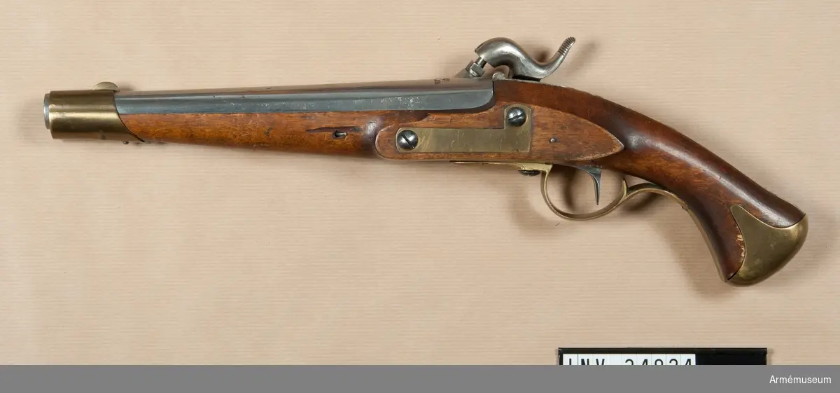 Grupp E III c.
Tappstudsarpistol med slaglås, reparationsmodell.
På kammarstycket tre kronor och på snäckan en krona. Pistolen har beslag för löskolv. (Pistolen är exakt lika  AM 34822, vilken uppges vara m/1820-1857).