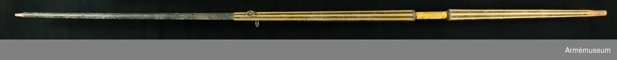 Fanstång i lansform av furu med kannelerad yta målad i svart och guld. Handgreppet är slätt och klätt med gul sidendamast. 

Övre delen av stången slät, nedanför greppet avsmalnande. Toppen snidad för fästandet av spets och holk. 130 mm nedanför den främre, släta delen finns två järnringar för fästande av fanstänger.