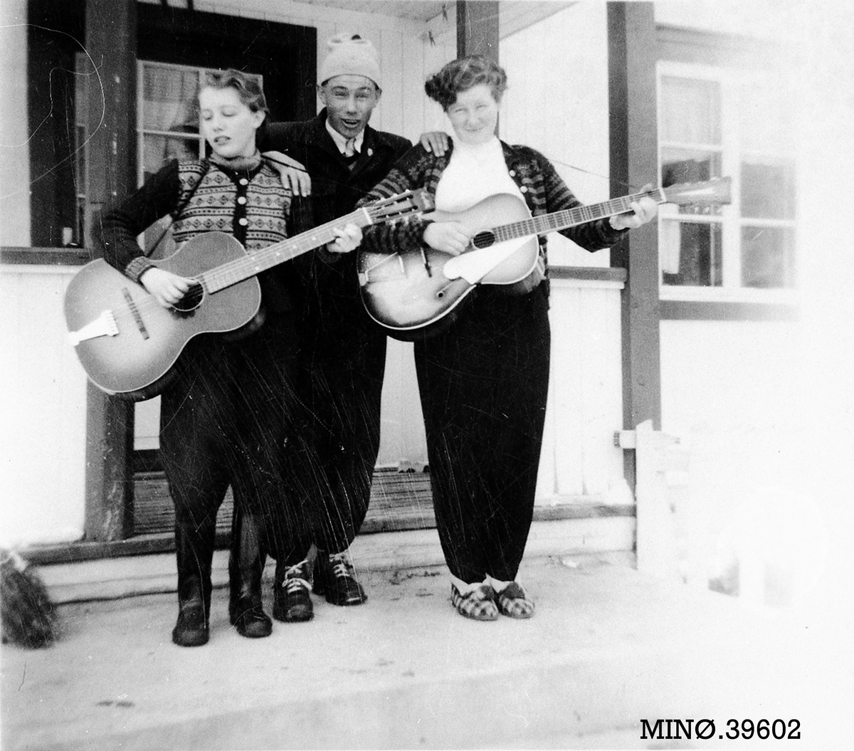 Kvinner som spiller gitar med ung mann mellom seg