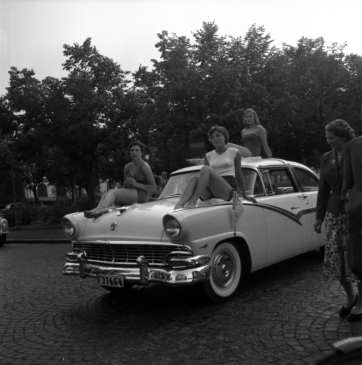 Bilkortege i Huskvarna. På bilens huv till vänster Fröken Fransén och till höger fröken Josefsson. 1950-tal.