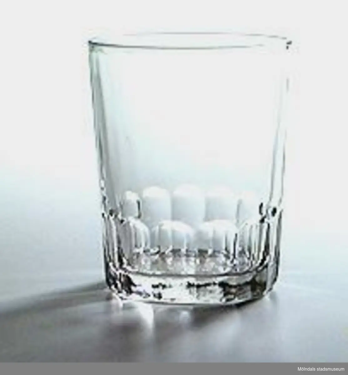 Dricksglas i tjockt, slagtåligt glas, rakt, med facettimiterad nederkant. Mycket vanligt bruksglas (1992).