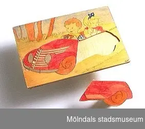 Kontursågat i plywood, motiv "barn i bil". Ingår i Holtermanska samlingen.
