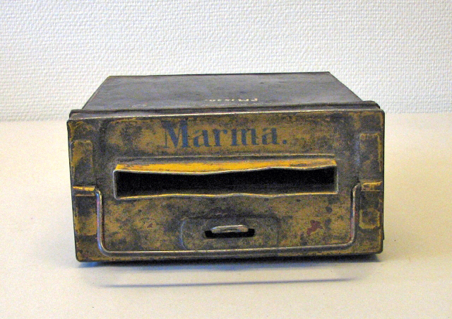 Insatsbrevlåda avsedd för placering i brevlådeställ med text
"Marma" i blått. Svartmålad med gult tak. Ett brevinkast på ovansidan
samt handtag.