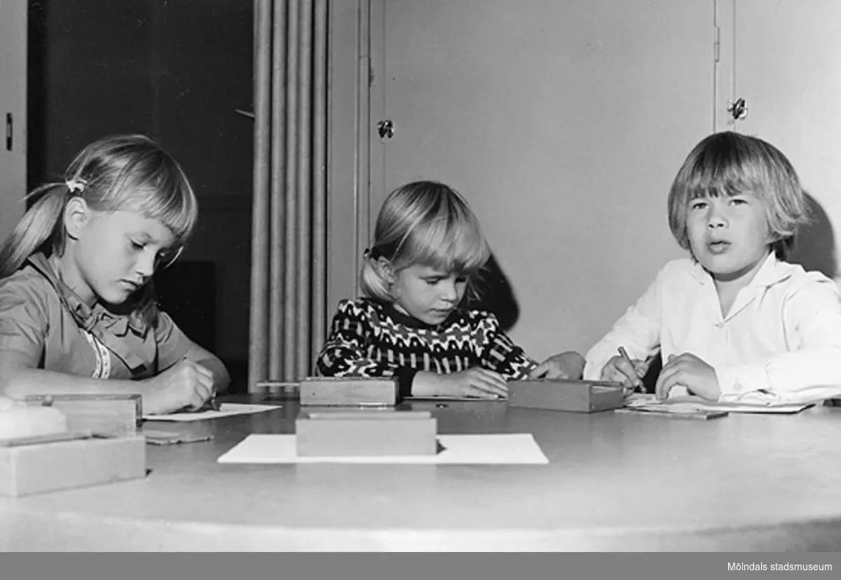 Tre barn som ritar vid ett bord. Holtermanska daghemmet 1953.