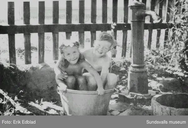 Bernt Edblad (f. 1938) och grannflickan Marianne badar i balja i familjen Siri och Erik Edblads trädgård, Södermalmsgatan 8, 1947. Familjen bodde här 1939 - 1960. Fastigheten ägdes av Helfrid Renström, som bodde i husets undervåning.