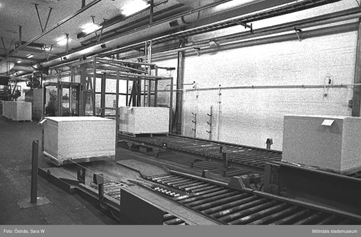 Interiör där pappersbalar går på löpande band i pappersfabriken.
Bilden ingår i serie från produktion och interiör på pappersindustrin Papyrus1980-tal.