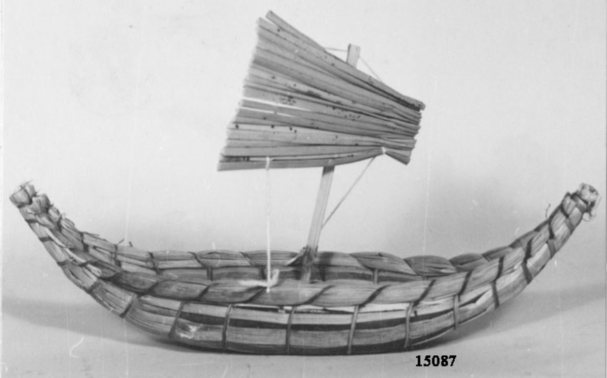 Balsabåt, modell.
Består av två hopsurrade flytkroppar av vass, som vardera relingen har en mÃ­ndre vasskropp.
Båten har uppsvängd för- och akterstäv samt har mast med segel av vass.