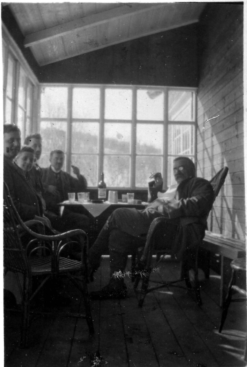 Selskap på glassverandaen på hytta Lia i Melbu-marka påsken 1922. Fem personer. Chr. Frederiksen til høyre.
