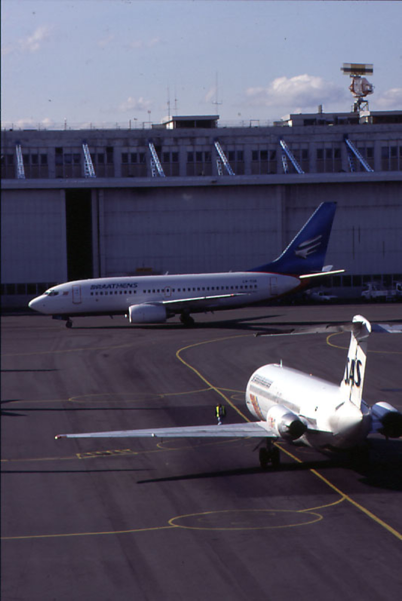 Lufthavn, 1 fly på bakken, Boeing 737-705, LN-TUA "Ingeborg Eriksdatter" fra Braathens.  1 fly fra SAS i forgrunnen, terminalbygningen i bakgrunnen.