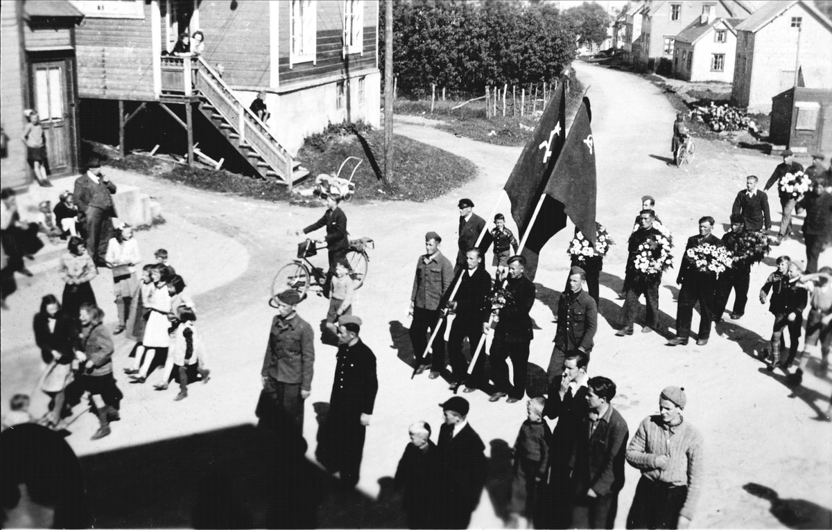 Russefanger marsjerer gjennom byen i forbindelse med kransenedlegging og avduking av minnebauta på Trondenes.