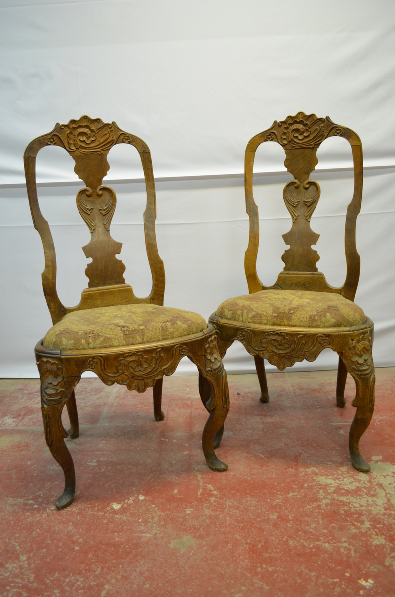 2 stolar med sete trekt i stoff (blomstrete) og treskjæring på stolrygg og stolbein.